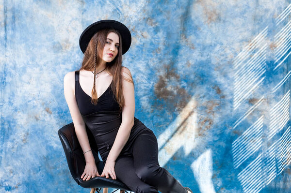 Studio shot of a magnificent young woman in elegant black clothes and classic hat. Beauty, fashion concept.