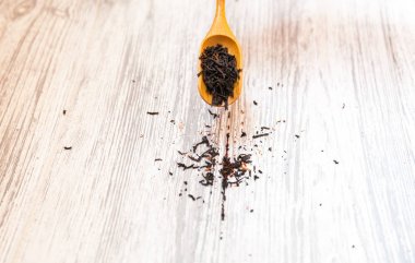 Gül yaprakları ile kompozisyon doğal siyah çay. Çay yaprakları gül tahta kaşıkla üzerinde makro fotoğraf. Çay çiçek ve çay ahşap bir gemide bulunan malzemelerle.
