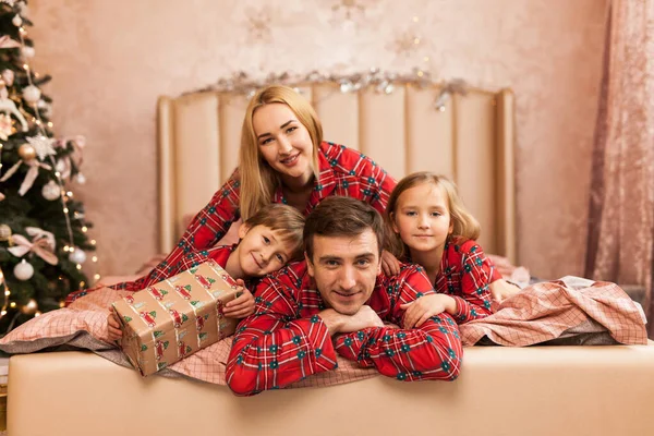 Šťastná rodina matka otec a děti na Vánoce ráno v posteli v pyžamu — Stock fotografie