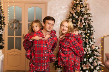 Kameraya gülümseyen iki çocuklu mutlu bir aile.