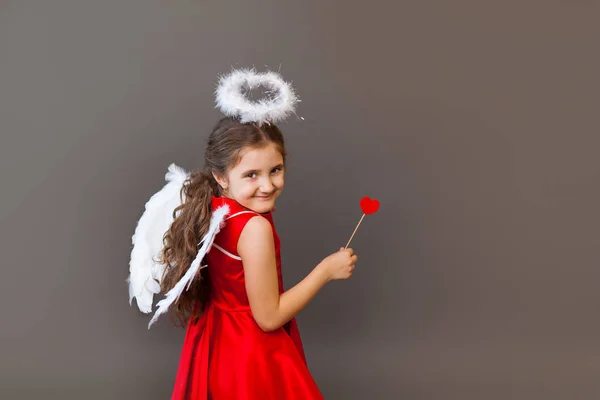 Menina sorridente Cupido anjo, com pirulito em forma de coração — Fotografia de Stock