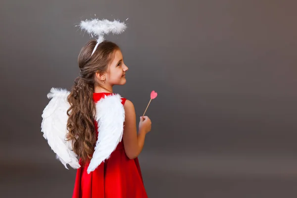 Smiling girl Cupid angel, with heart-shaped lollipop — Stock Photo, Image