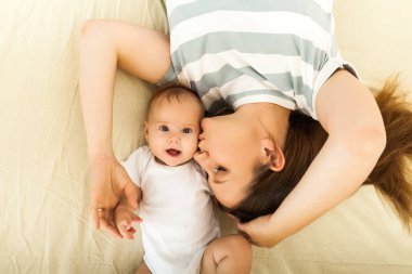 happy mother kissing a baby lying on a bed