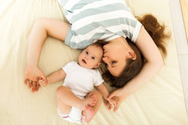 happy mother kissing a baby lying on a bed