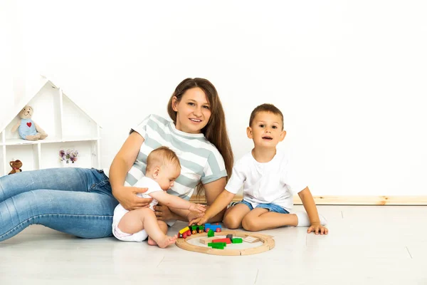 Matka siedzi z dziećmi gry w pomieszczeniach — Zdjęcie stockowe