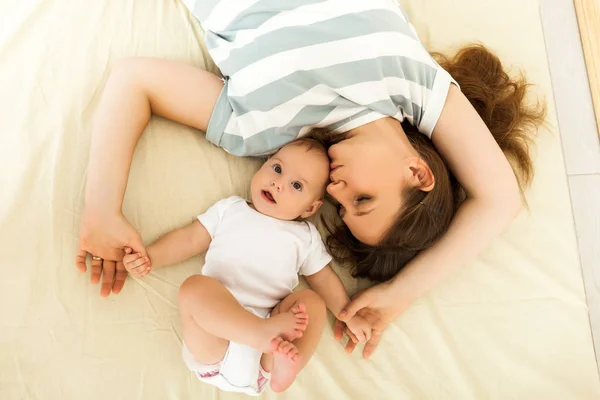 Happy mother kissing a baby lying on a bed — Stockfoto