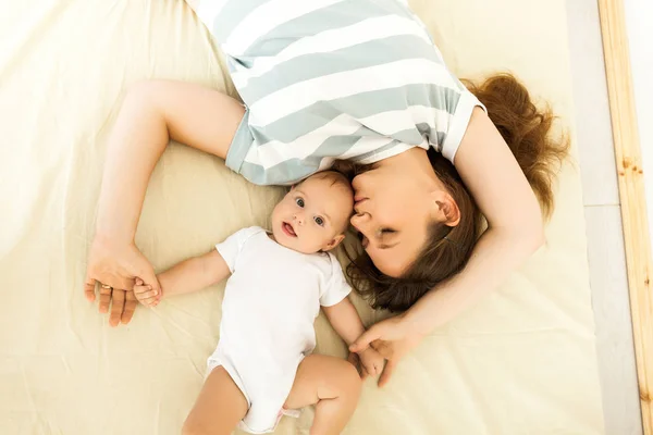 Happy mother kissing a baby lying on a bed — 스톡 사진