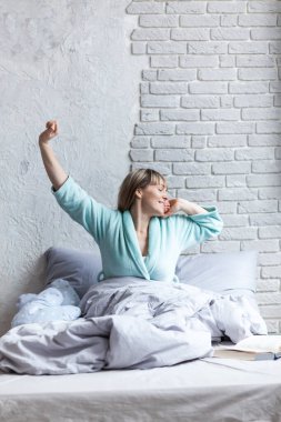 uyanma ve yatakta otururken bir streç ile esneme yorgun uykulu kadın