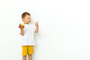 Oyuncak arabalı güzel bir çocuğun portresi beyaz arka planda sana onay veriyor.