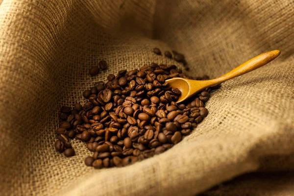 Coffee beans spilling from a burlap bag and a scoop on a textured map surface