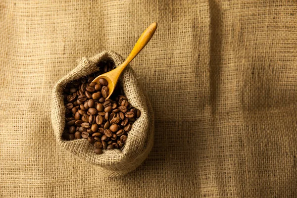 Burlap Hessian袋烤咖啡豆 有木制勺子 在工厂纹理背景上 — 图库照片