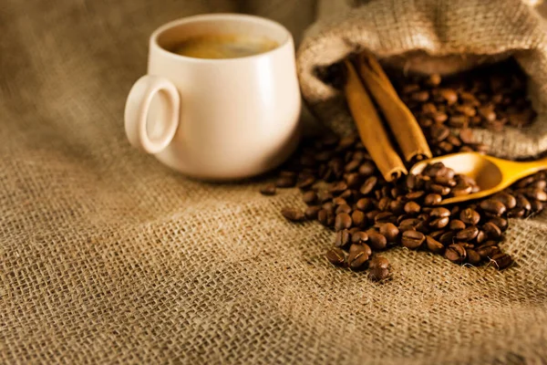 香り高いコーヒー シナモンスティック 袋からのコーヒーの散らばっ粒 そしてバラップからのテクスチャ工場ファブリック上の木のスクープ — ストック写真