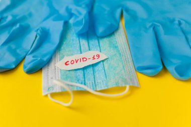 Sarı arka planda koruyucu maske ve eldivenler. Roman Coronavirus 2019-NCoV. Yazıt Coronavirüs 'ü durdurun..
