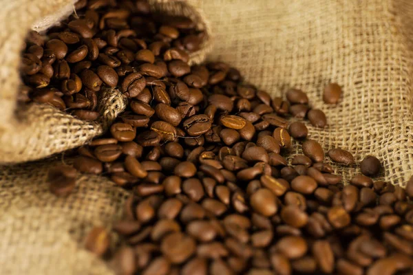 阿拉比卡咖啡颗粒分散在工厂纹理背景的袋子里 — 图库照片