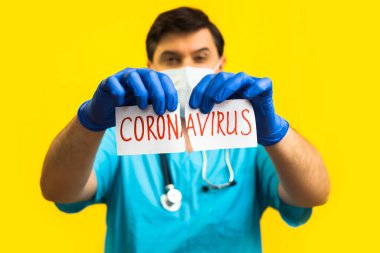 Koronavirüs karantinası kavramı. Roman Coronavirus 2019 NCoV. Sarı zemin üzerinde steteskopu olan doktor beyaz kağıdı Coronavirus sözcüğüyle yırt.