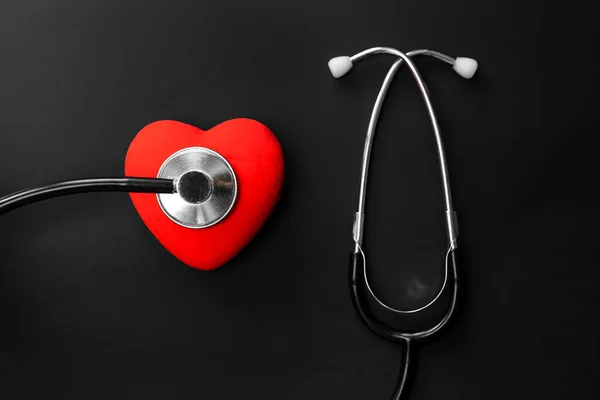 Top view Flat lay of accessories essential items for doctor, healthcare and medical background concept. Red heart and stethoscope on Black background with Copy space. Heart check concept healthcare