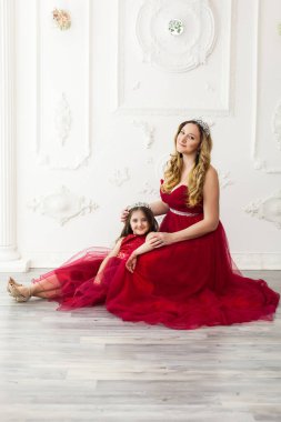 Anne ve kızı aynı kıyafetlerle fotoğraf stüdyosunun içinde poz veriyorlardı. Kırmızı elbiseler giyiyorlardı. Aile görünüşü