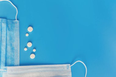 Solunum maskesi ve hapları olan mavi arkaplan Coronavirus mavi arka planı, kopyalama alanı olan mavi arkaplan üzerine seçici odaklanma