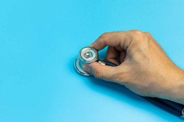 Doktorlar Bir steteskop tutuyor açık mavi arka plan yatay formatı kapalı