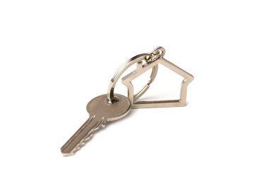 Beyaz zemin üzerinde ev figürü olan gümüş anahtarın makro görünümü