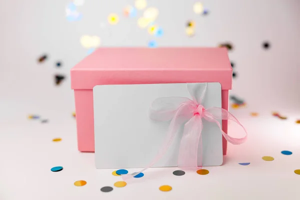 Pink gift box with gift or voucher card on white background. Card with pink ribbon for commerce shopping on winter holidays birthday Party concept.