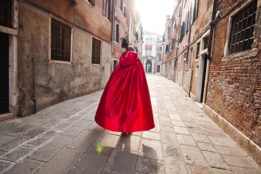 Bir kadında bir kırmızı pelerin Venedik caddeden aşağı doğru koşar