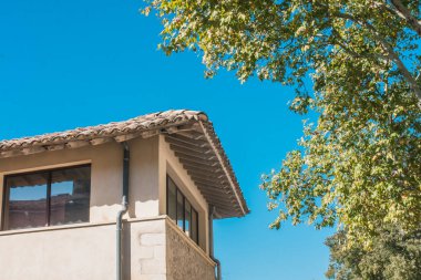 Evin ikinci tavan arası zeminine karşı gökyüzü ve ağaç dalları.