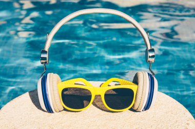 Disko yazında moda sarı plastik çerçeveli güneş gözlüğü ve müzik kulaklığı.