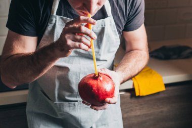 Şef nar sulu olgun meyveye bir kokteyl çubuğu yerleştirdi. Sağlıklı yiyecekler.