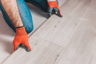Döşeme döşemesi yerleştirilirken ustanın elinin yakınlaştırılması - döşeme kurulumu