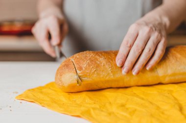 Avrupalı kadın elleri tahtadan taze ekmek kesiyor.