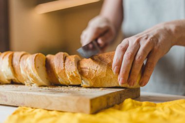 Avrupalı kadın elleri tahtadan taze ekmek kesiyor.