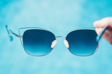 Plajda güzel, modaya uygun güneş gözlükleri. Gök mavisi suyun arkaplanına karşı. Yaz tatili.