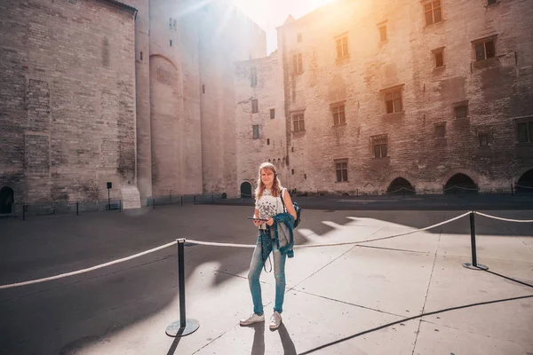 Pleasant nice attractive blonde girl in the Avignon Palace on an excursion with an audio guide