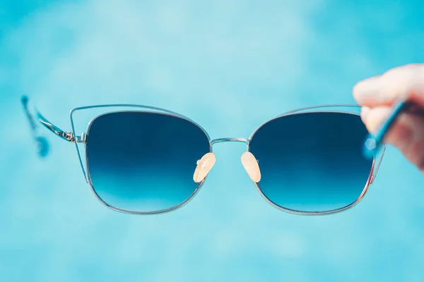 Beautiful fashionable sunglasses on the beach against the backdrop of azure water - summer resort