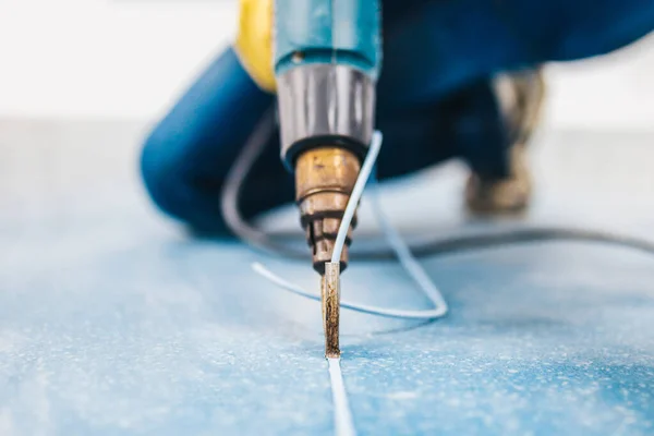 Linolyum çivi teknolojisi - kaynak makinesi sıcak havanın yardımıyla bir uzmanın ellerinde