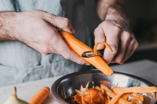Грубые Мужские Руки Чистят Морковь Специальным Ножом Заднем Плане Кухни — стоковое фото