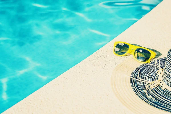 Tatil konsepti - yakın çekim güneş gözlüğü ve havuz kenarında güneşli bir günde bayan şapkası - fotokopi alanı