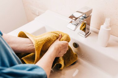 Banyodaki kadın ellerini yıkadıktan sonra havluyla siler.