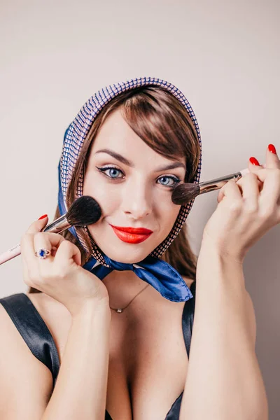 Caucasian girl with make-up brushes - attractive fun playful girlfriend on self-isolation at home