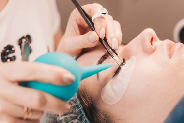 Kirpik uzatma prosedürü. Usta, plastik şırıngadaki havayla yapıştırıcıyı kurutuyor.