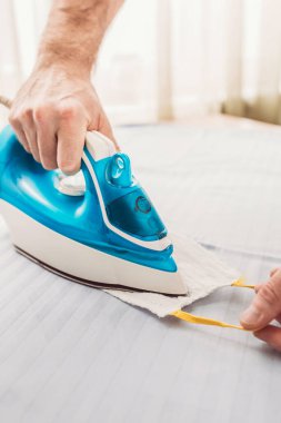 Bir adam bir ütüyle gazlı bez maskesini ısıtır - bakterileri yok eder - antibakteriyel tedavi - cerrahi steril maske - koronavirüsün yayılmasına engel olur