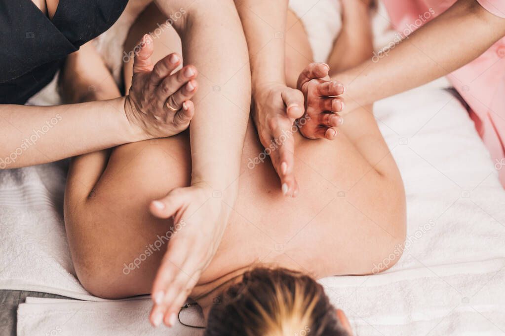 Symmetrical work of two massage therapists at the same time - effective Thai relaxing four-hand massage