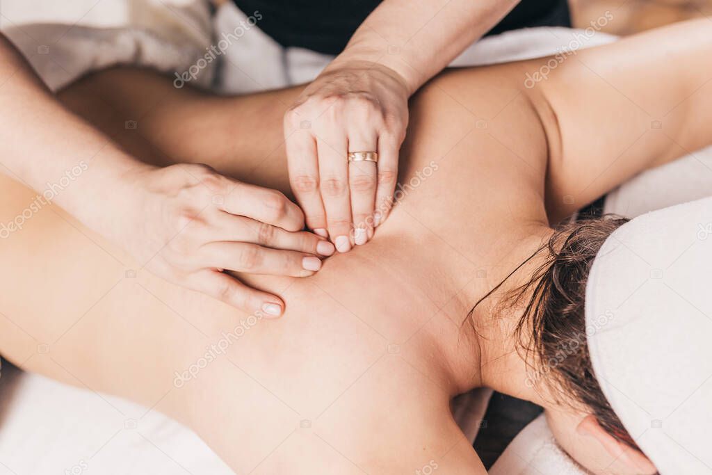 Hands of a masseuse on a female back during work - treatment of diseases of the back and spine - elimination of back muscle clamps