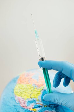 Dünyanın arka planına karşı iğneyle yapılmış bir şırıngada Coronavirus aşısı. Doktorlar ve bilim dünyayı bir salgından kurtardı.