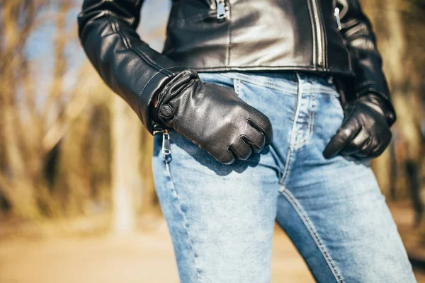 Woman in jeans and a black leather jacket with black gloves - rocknroll style - girl motorcyclist - stylish and independent woman