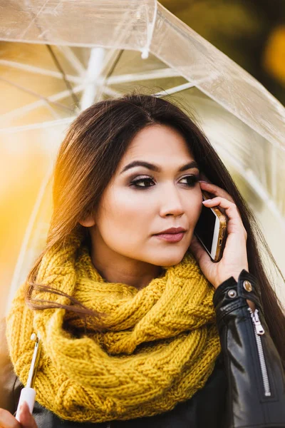 bright independent successful woman with a phone under an umbrella on the street