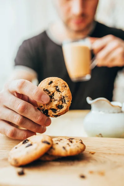 A man eating breakfast of cookies and cocoa with milk - homemade oatmeal cookies with chocolate chips - English breakfast close-up