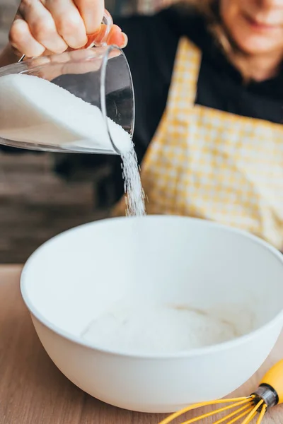 Charlotte apple pie baking - Woman pours sugar from a glass into a white bowl for dough