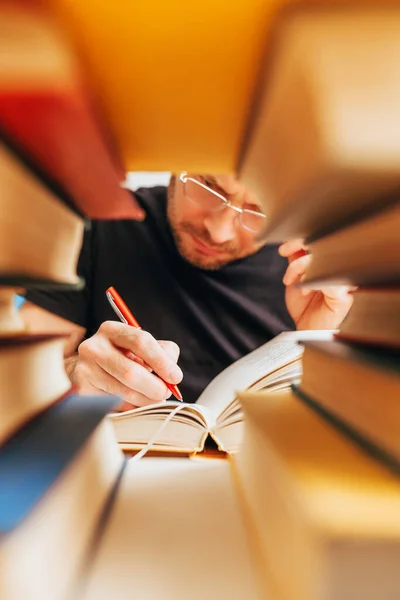 一个戴眼镜的人在一本书里写笔记 书里面有一个笔头研究图书馆里的印刷品 — 图库照片